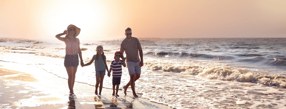 Family walking along a beach at sunset